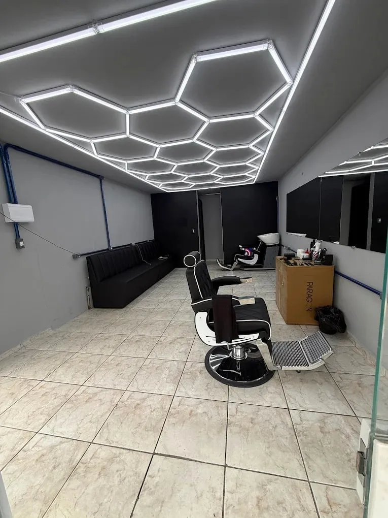 Salão da Dom Rocha com o teto de LED hexagonal, cadeira de barbeiro e sofá de espera